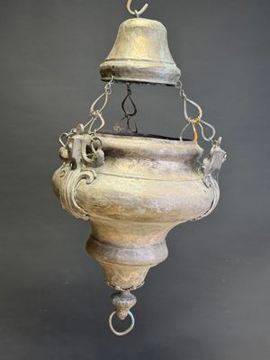 an old metal hanging light fixture with a bell on top of it