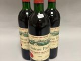 trois bouteilles de vin rouge posées sur une table blanche