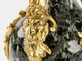 a green and gold vase with a lion head on it