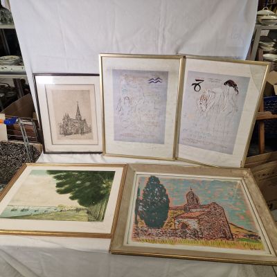 Trois photos encadrées représentant des bâtiments et une église sont posées sur une table devant un fond blanc.