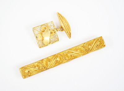 two pieces of gold jewelry on a white surface with a white background
