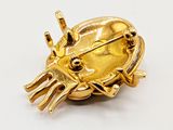 a gold crab brooch on a white surface