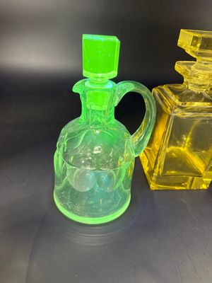 des flacons de parfum en verre jaune et vert posés sur une surface noire