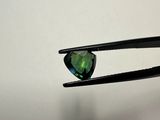 a close up of a pair of pliers holding a green tourmaline stone