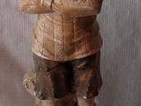 une statue en bois représentant un homme coiffé d'un chapeau