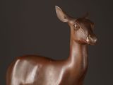 bronze statue of a deer on a wooden base against a black background