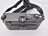 a black camera with a strap around it on a white surface