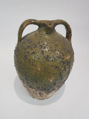 un vase vert posé sur une surface blanche