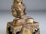 une statue en or représentant Bouddha assis sur un banc, sur fond blanc