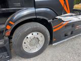 a black semi truck with orange stripes parked in a parking lot