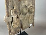 an old wooden door with a metal latch on a stand