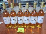 Six bouteilles de vin sont alignées sur une table, accompagnées d'une étiquette de prix