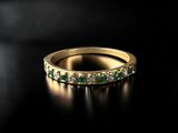 a gold ring with emerald stones on a black background
