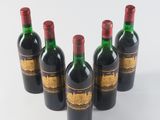 six bottles of wine are lined up in a row on a white surface