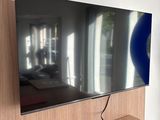 a flat screen tv sitting on a desk in front of a window