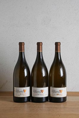 three bottles of wine sitting on a wooden table next to a bottle of wine
