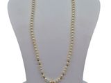 a close up of a necklace with pearls on a mannequin