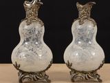 pair of silver and white glass vases sitting on top of a wooden table