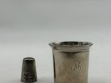 an antique silver thimble next to a silver thimble on a white surface