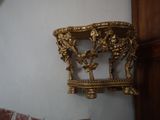 une horloge accrochée au mur, à côté d'une étagère dorée