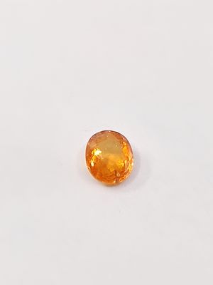 an orange sapphire stone on a white surface