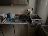 une photo d'une cuisine avec de nombreux ustensiles posés sur le plan de travail