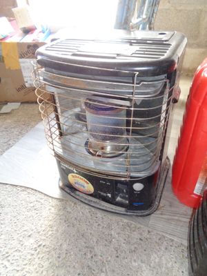 une valise rouge posée par terre à côté d'un radiateur d'appoint