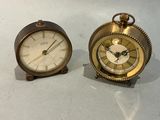 two clocks sitting next to each other on a table