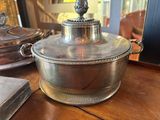 a silver casserole sitting on a wooden table