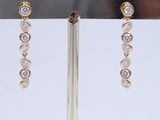 pair of gold and diamond earrings on display on a stand