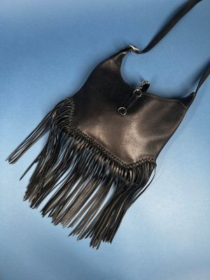 a black purse with fringes hanging from it ' s side against a blue sky