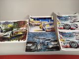 Plusieurs tableaux représentant des voitures de course sont exposés sur une table