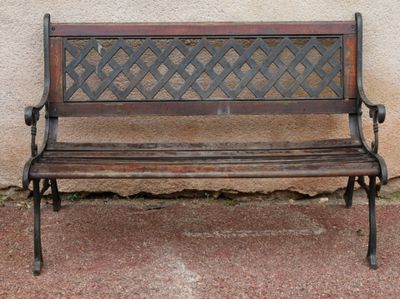 a wooden bench sitting on the sidewalk near a wall