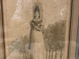 a framed picture of a woman in a dress and hat