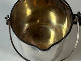 a silver bucket with a handle on a white table