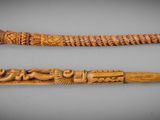 two carved wooden sticks with carvings on them sitting on a table