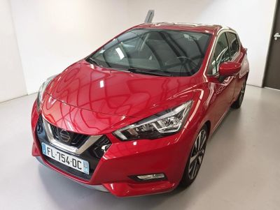 Une voiture rouge est garée dans une pièce blanche dont la porte est ouverte.