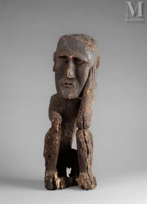 une vieille sculpture en bois représentant un homme les mains sur le visage