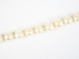 un gros plan d'un collier de perles sur une surface blanche