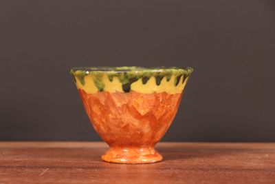 un petit bol orange posé sur une table en bois