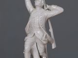 a white statue of a man holding a sword on a table