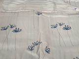 un couvre-lit orné de fleurs bleues, posé sur des palettes dans une pièce
