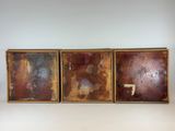 trois tableaux accrochés au mur d'une pièce aux murs blancs