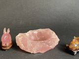 three small figurines of animals and a rock on a table