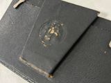 an old black book with a key on top of it sitting on a table