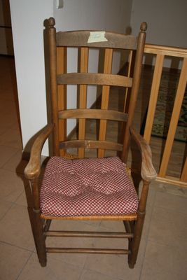 a wooden rocking chair with a red and white checkered seat pad