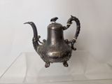 a silver tea pot sitting on a glass table