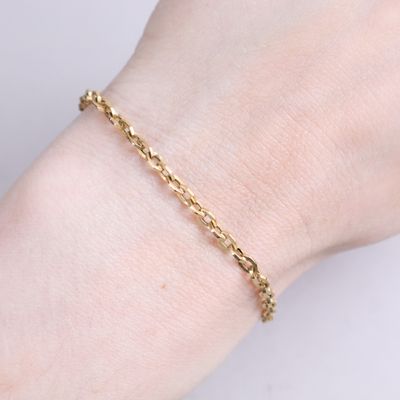 a close up of a woman ' s hand wearing a gold chain bracelet