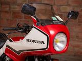 a red and white motorcycle parked in front of a brick wall