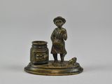 an antique bronze figurine of a boy with a jar of honey